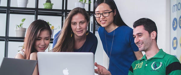 Four students looking at one laptop (c) Unsplash